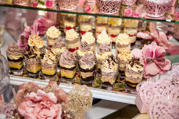 Delicious desserts at the wedding candy bar in the buffet area: glasses with layered dessert with chocolate, cream, nuts, souffle, whipped cream