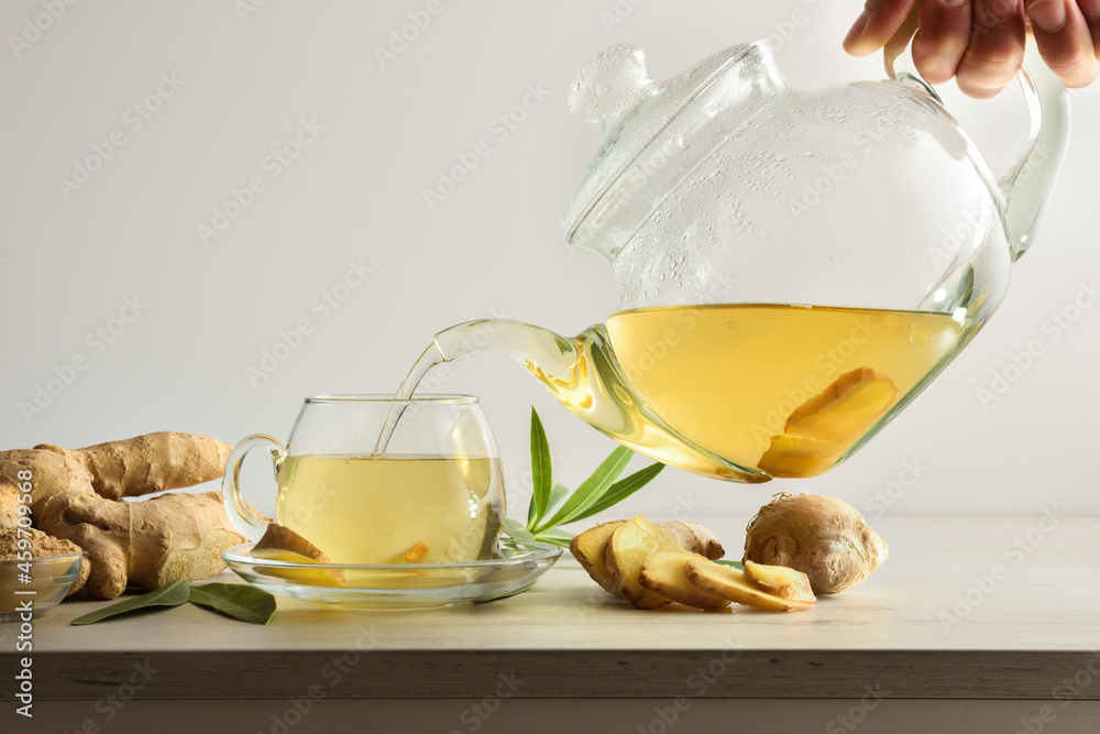 Wall mural Man serving cup with ginger root infusion on bench isolated