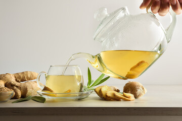 Man serving cup with ginger root infusion on bench isolated