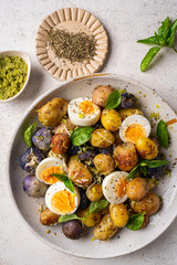 Homemade salad of new colorful potatoes, quail eggs and pesto, top view