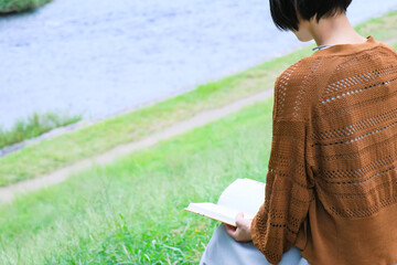 河原で読書するショートへアの女性モデル
