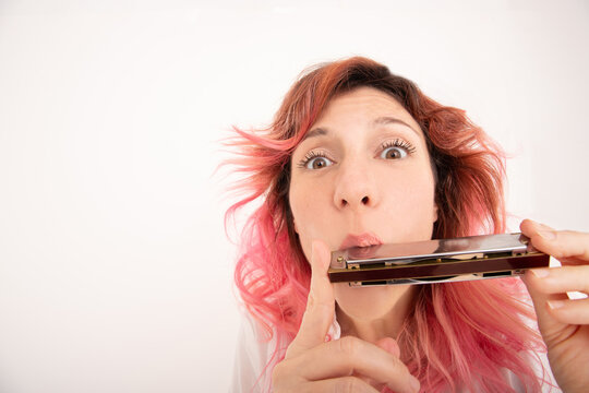 Female playing harmonica in light room