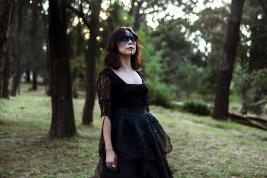 Witch in black dress in dark forest