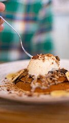 person eating a pancake with a scoop of ice cream and nuts