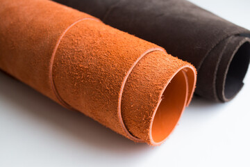 Rolls of brown and black leather on a white background