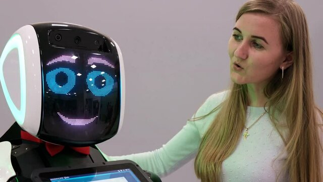Visiting woman talking to a humanoid robot.The robot with the display shows emotions, talks
