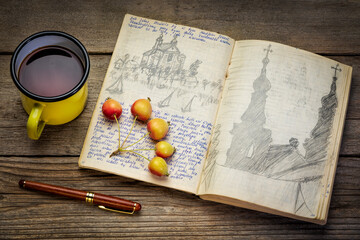 Vintage travel journal with handwriting and pencil sketches (property release attached) on rustic table with tea - kayak expedition in Poland 1970s.