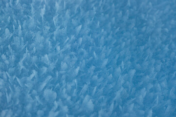 Snow texture with snowflakes close-up. Blue macro image of an abstract snowdrift. Crystal snow minimal texture pure. Winter landscape background.