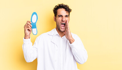 hispanic handsome man feeling happy,giving a big shout out with hands next to mouth. chiropodist...