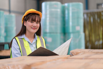 Asian female engineer hold document folder checking product stock inventory in warehouse factory industrial
