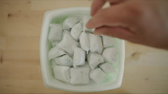Man retrieves Dish Detergent Laundry soap pod packet to do chores in kitchen