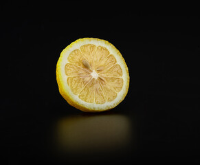 A slice of fresh juicy lemon on a glossy black surface