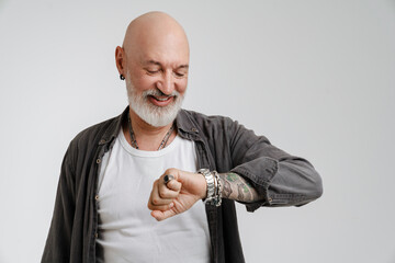 Bald european man with beard laughing while looking at wristwatch