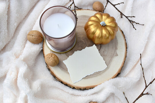 Fall mockup composition with empty blank invitation, decor pumpkin and aroma candle on cosy plaid.  Walnuts. Minimal mock greeting scene for autumn wedding, Thanksgiving. Eco home concept.