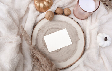 Fototapeta na wymiar Cozy autumn or winter layout still life. Mockup invitation card, candles, pumpkins wooden tray on white blanket. Nordic home decor flat lay for autumn wedding, Thanksgiving, Christmas holidays.