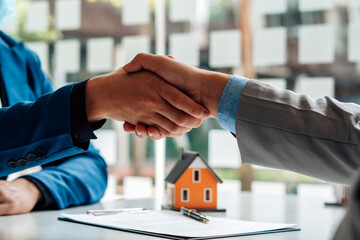 Real estate broker and customer shaking hands after signing a contract: real estate, home loan and insurance concept