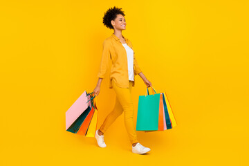 Full length body size photo woman walk with packages on sale isolated vivid yellow color background