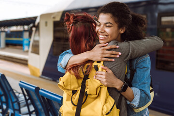 Multiracial two women hugging while saying goodbye at train station
