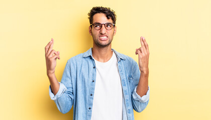 hispanic handsome man crossing fingers and hoping for good luck