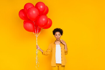 Photo of young black girl amazed shocked many balls inflate birthday surprise isolated over yellow color background