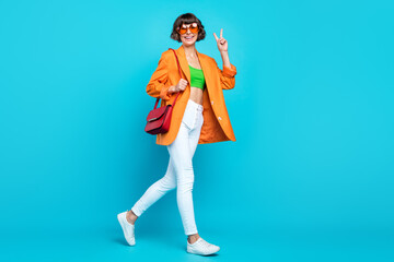 Full length profile photo of sweet millennial brunette lady go wear blazer spectacles top jeans shoes isolated on teal background