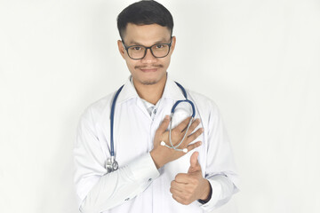 Portrait of doctor with hand touching heart and showing thumb up on white background.