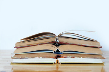 a stack of open books on a wooden table on a white background