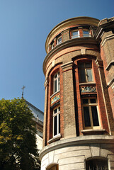 Fototapeta na wymiar Curved Brick Facade of 19th Century Building seen from below against Blue Sky