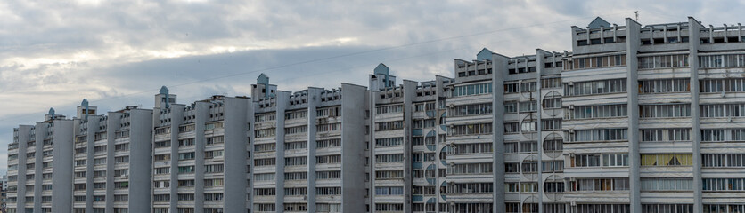 Bottom view of a multi-storey panel residential building on dramatic sky background. City life view.