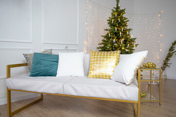Living room with a sofa and a large Christmas tree and copy space over white wall with lights. New Year's interior