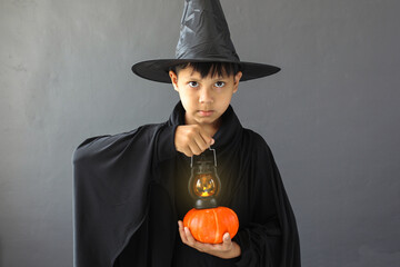 A boy with halloween costume and holding a lantern and pumpkin