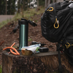the concept of a snack in a hike through the forest in the fresh air. Delicious kabanos, pate and hot tea in a thermos