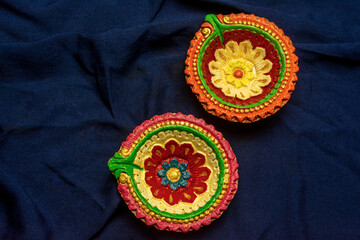 Happy Diwali - Colorful clay diya or oil lamps on blue background.