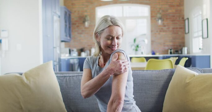 Portrait of happy senior caucasian woman in living room with bandage on her arm