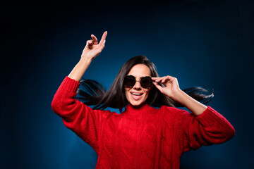 Photo of funky pretty young lady wear knitted sweater dark glasses smiling dancing isolated gradient blue color background