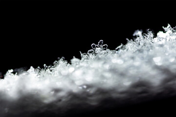 Natural snow texture with snowflakes close-up on the window, isolated on black background. Blank for holiday gift cards. Macro texture of snow, snowflakes.