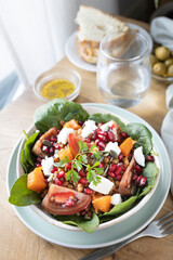 Lentil salad with pumpkin, tomatoes, pomegranate seeds, spinach and goat cheese. Refreshing legume and vegetable salad. Vegetarian food photography
