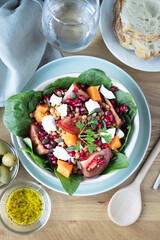 Lentil salad with pumpkin, tomatoes, pomegranate seeds, spinach and goat cheese. Refreshing legume and vegetable salad. Vegetarian food photography
