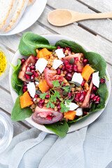 Lentil salad with pumpkin, tomatoes, pomegranate seeds, spinach and goat cheese. Refreshing legume and vegetable salad. Vegetarian food photography
