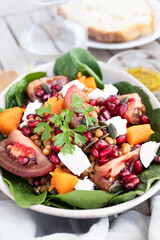 Lentil salad with pumpkin, tomatoes, pomegranate seeds, spinach and goat cheese. Refreshing legume and vegetable salad. Vegetarian food photography
