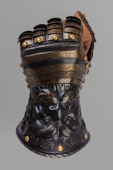 Medieval knightly brown plate gauntlet from Italian armor, in the form of a lion's face and mane,...