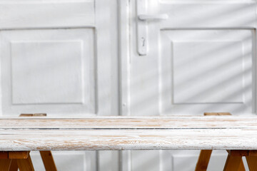 Wooden white table against a background of white doors with a lift on a beautiful warm day