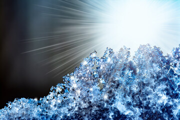 Natural snow texture with bright rays of the sun and sun glare. Close-up texture of snow on the window in soft blue tones. Creative winter festive background.