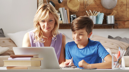mother and her student son use the computer together sitting in the living room at home, with a credit card they surf the internet looking for a purchase, shopping online concept