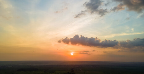 Obraz premium Bright colorful sunset sky with setting sun and vibrant clouds over dark landscape.