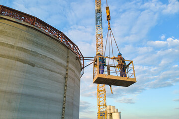 Aerial view of workers on cement factory under construction with high concrete plant structure and...