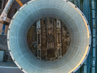 Fototapeta premium Aerial view of cement factory under construction with high concrete plant structure and tower cranes at industrial production area. Manufacture and global industry concept.