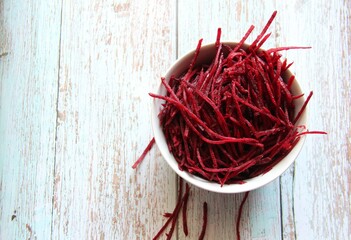 Beetroot, organic, raw, grated, isolated in a white bowl on an old wooden table. Upper view.
