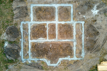 Top down aerial view of building works of new house concrete foundation on construction site.