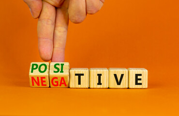 Positive or negative symbol. Businessman turns wooden cubes and changes the word 'negative' to 'positive'. Beautiful orange table orange background. Business, positive or negative concept. Copy space.